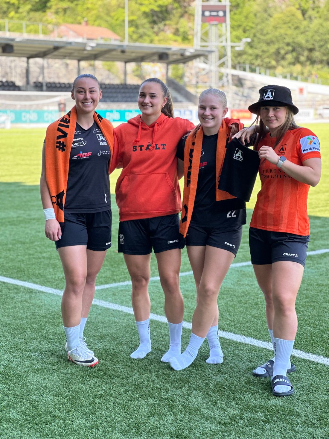 fire spillere fra Åsane fotball med merch på seg, de står sammen og smiler